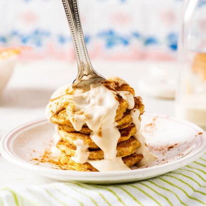 Mini Carrot Cake Pancakes with Vanilla Greek Frosting from Holley Grainger - Image of four cakes stacked on plate, dripping with icing and speared by a fork